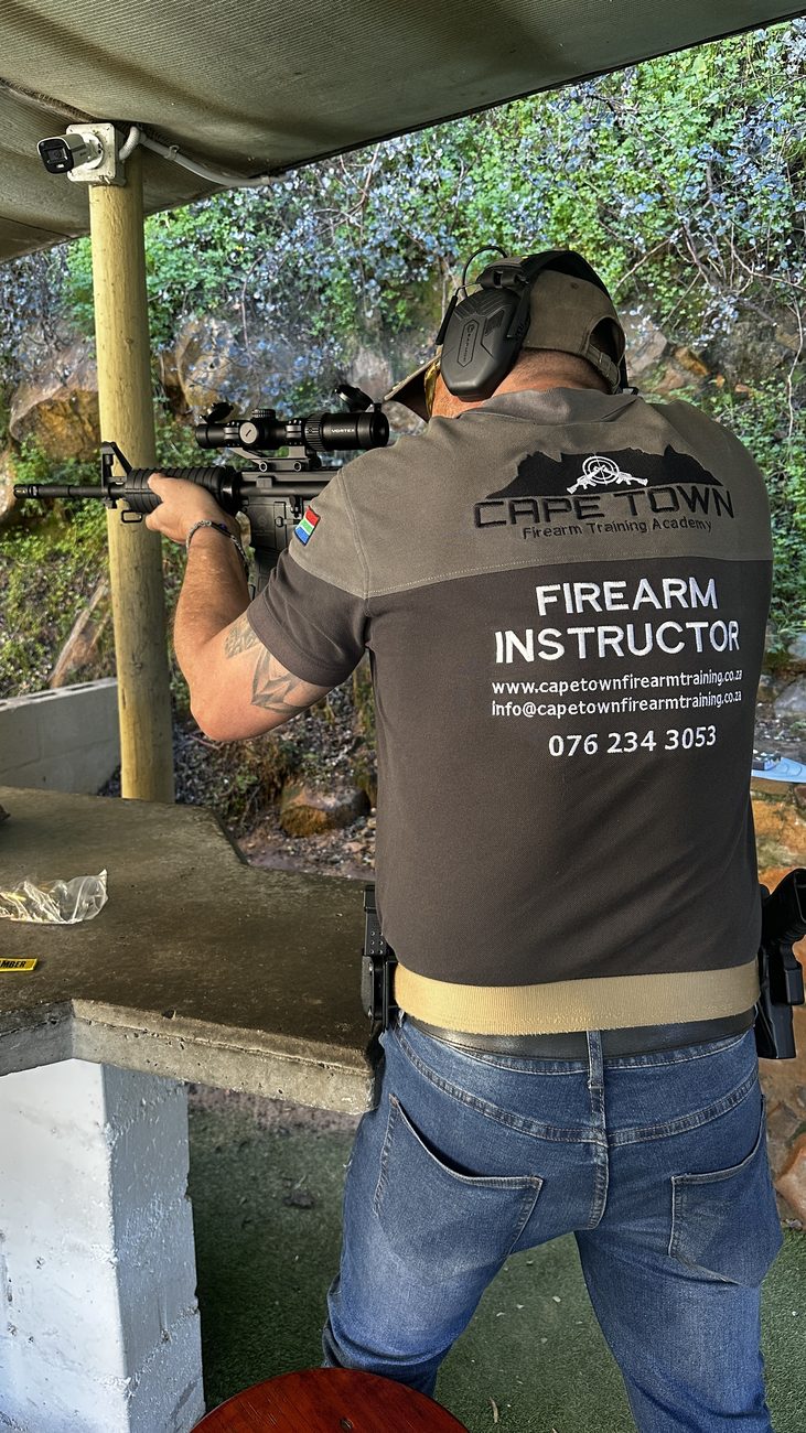 Cape Town Firearm Training Academy instructor on the range with a self-loading rifle, wearing the academy firearm instructor shirt
